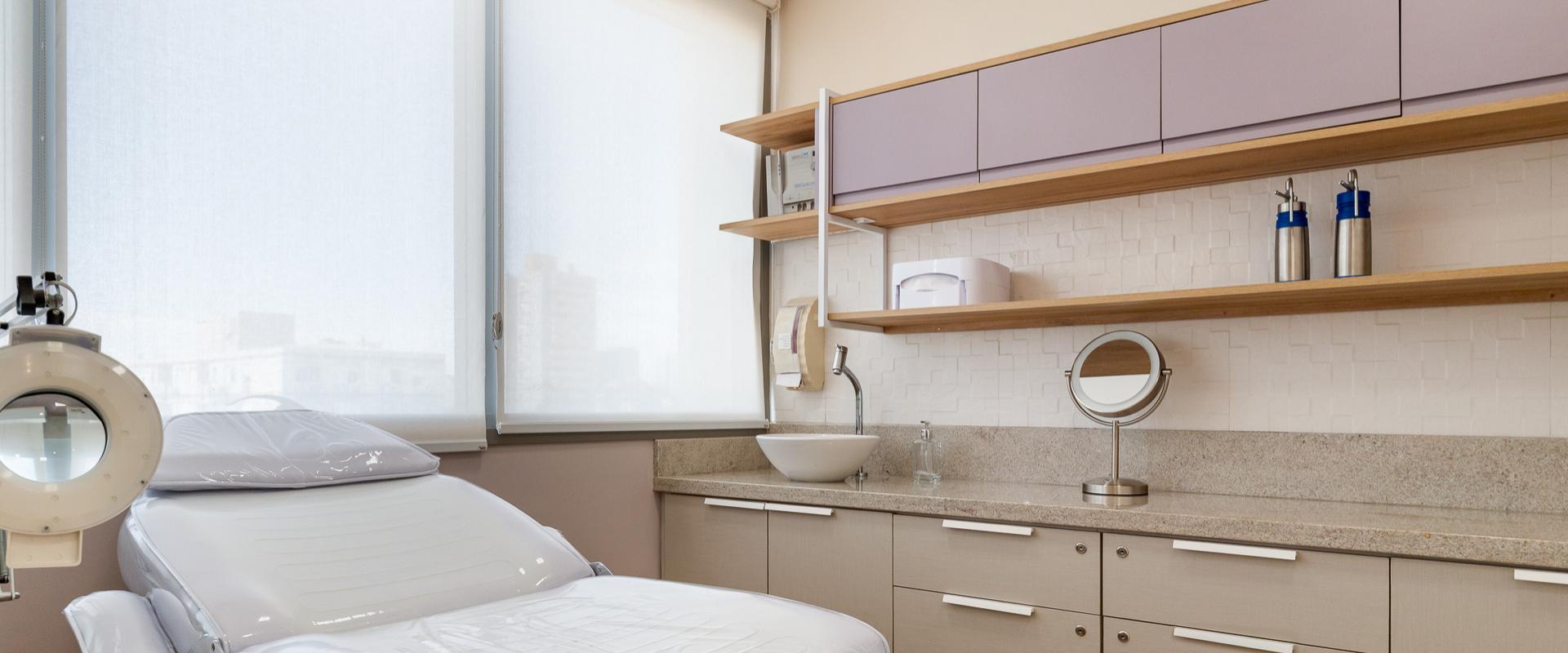 Consultório de estética projetado com marcenaria lilás, bancada em granito e iluminação natural, design de interiores para clínica de saúde