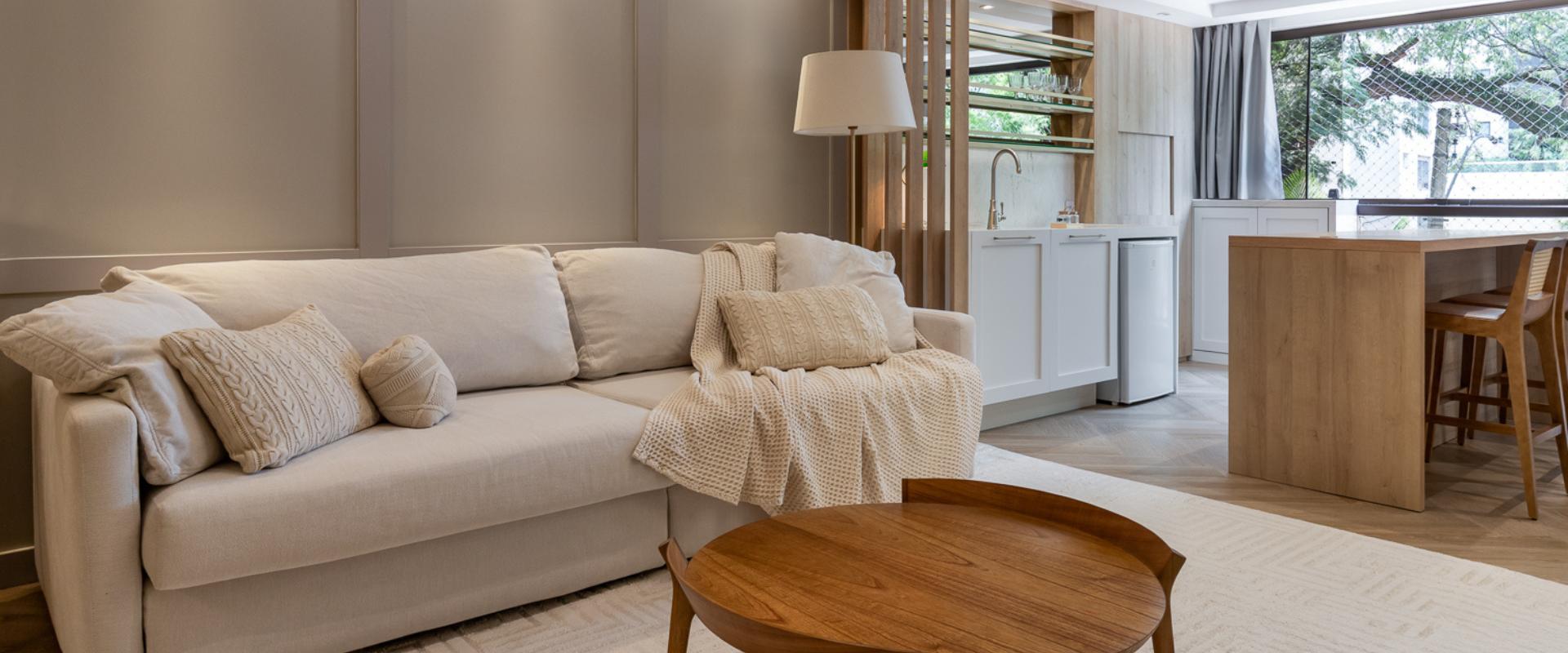 Sala de estar integrada a copa com sofá em linho bege, mesa de centro em madeira e vista para área externa, design de interiores residencial
